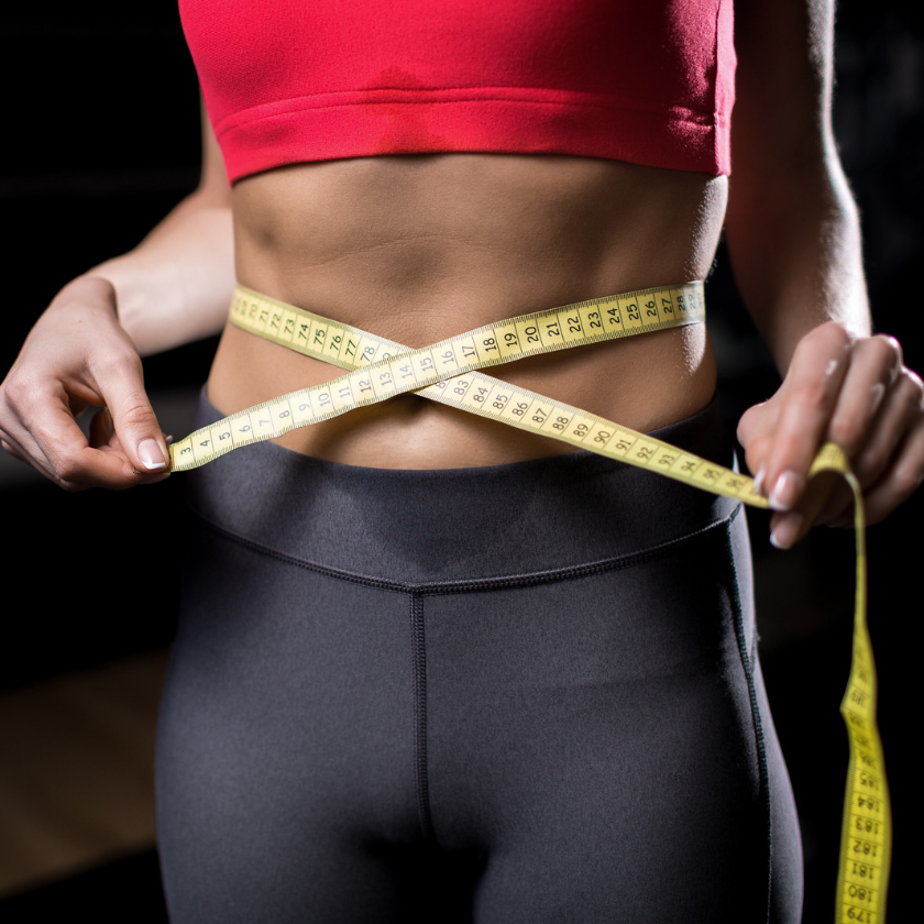 Woman's waistline with measuring tape showing inches lost.